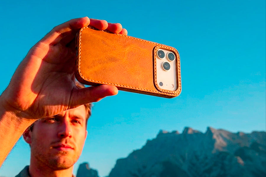 TRIM Honey leather iPhone case held outdoors, mountain scenery