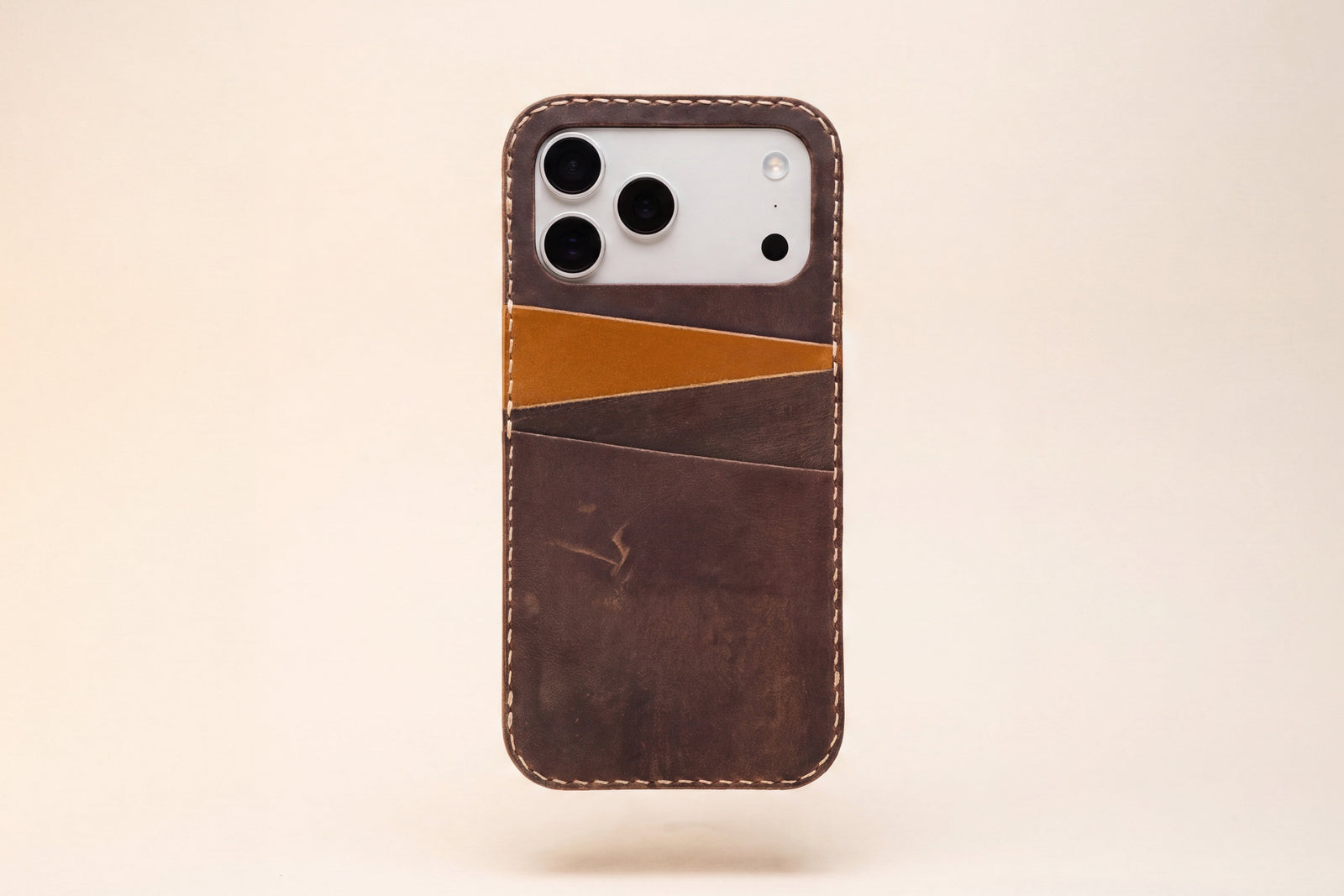 A walnut dark brown leather phone case with a minimalist card pocket design, shown floating against a solid light beige background.